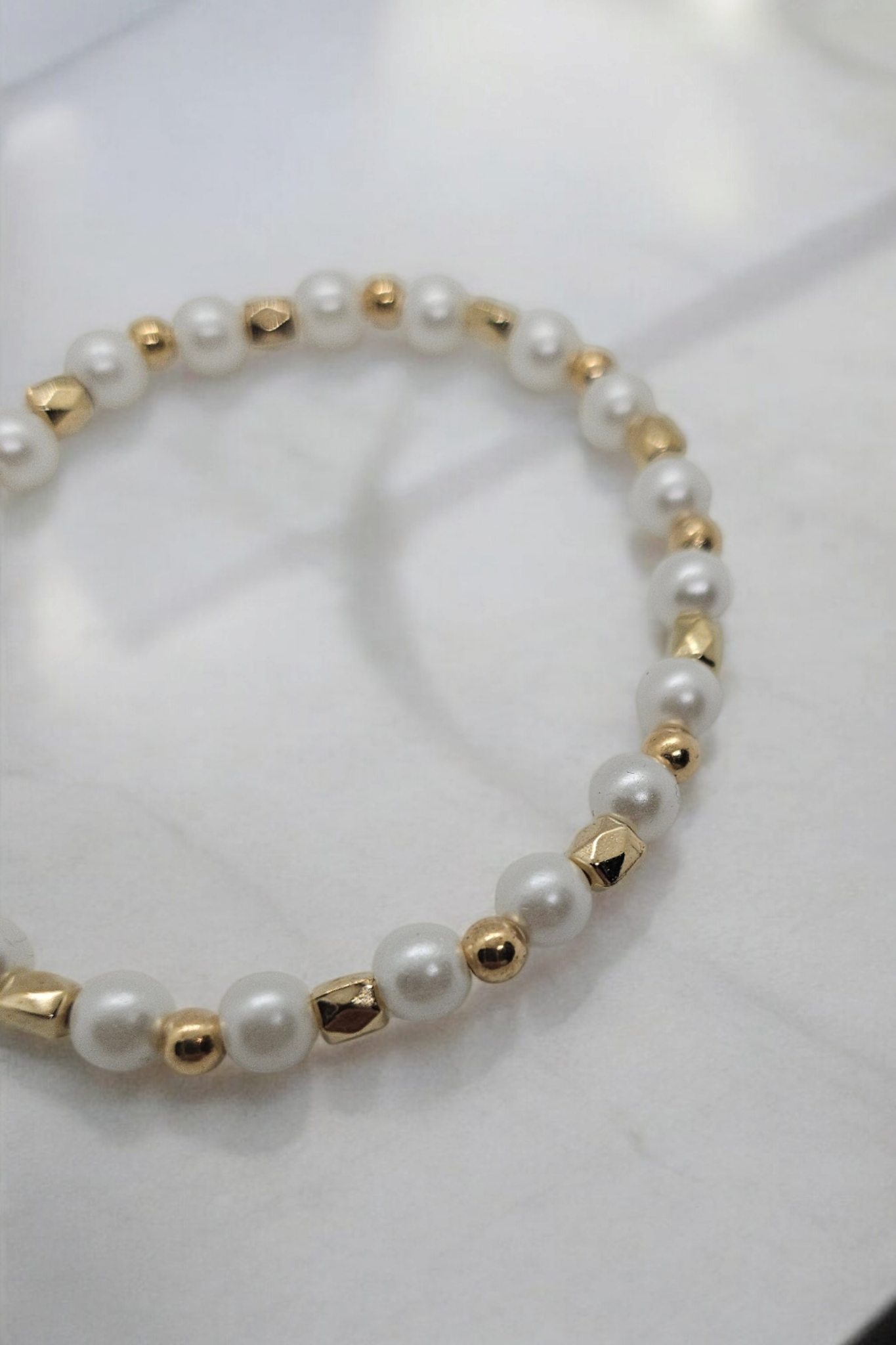 Goudkleurige elastieken armband met namaak parels en goudkleurige kralen