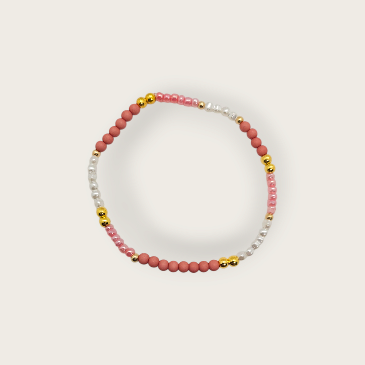 Armband van elastiek met roze kralen en goud en witte details