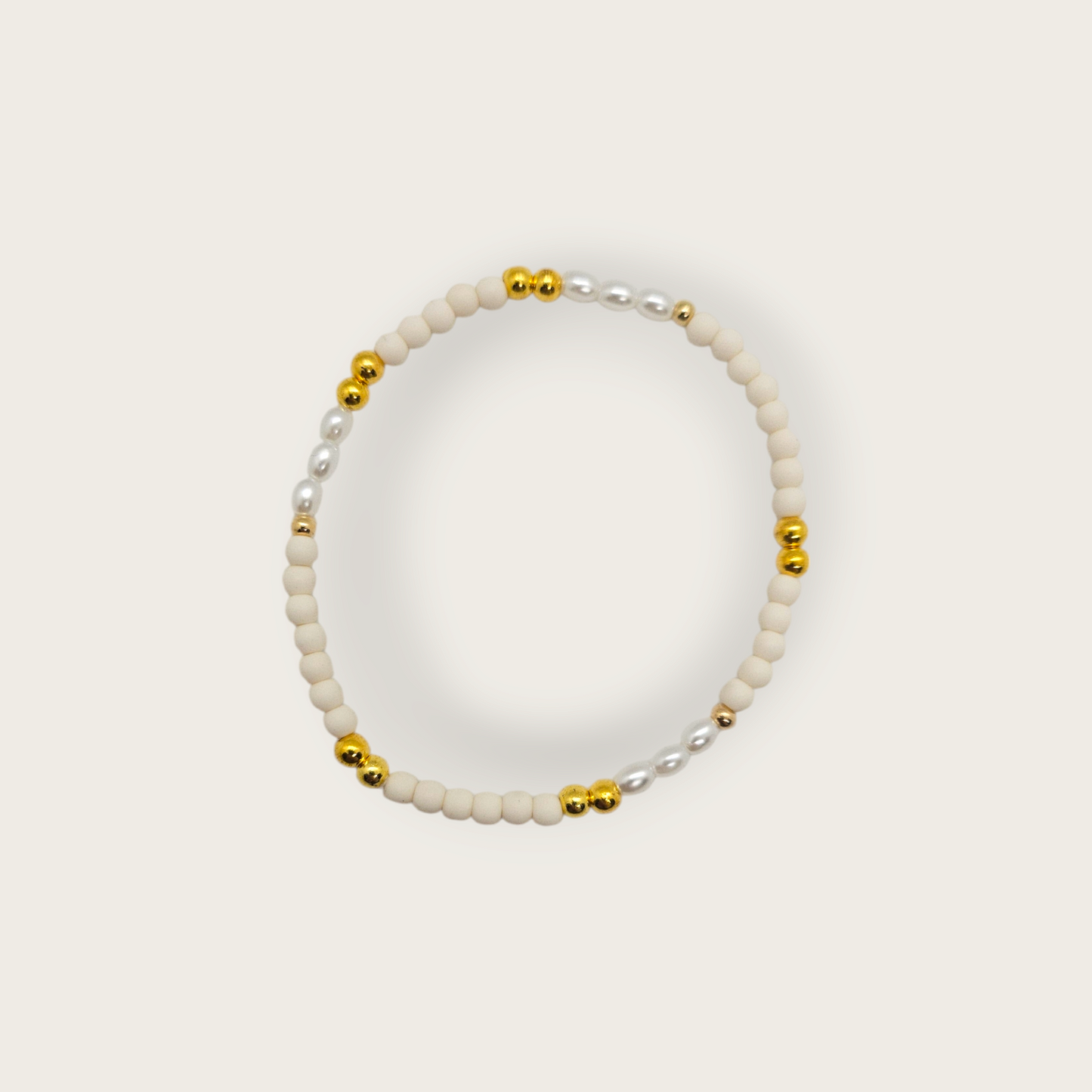 Elastieken armband met witte en gouden kralen