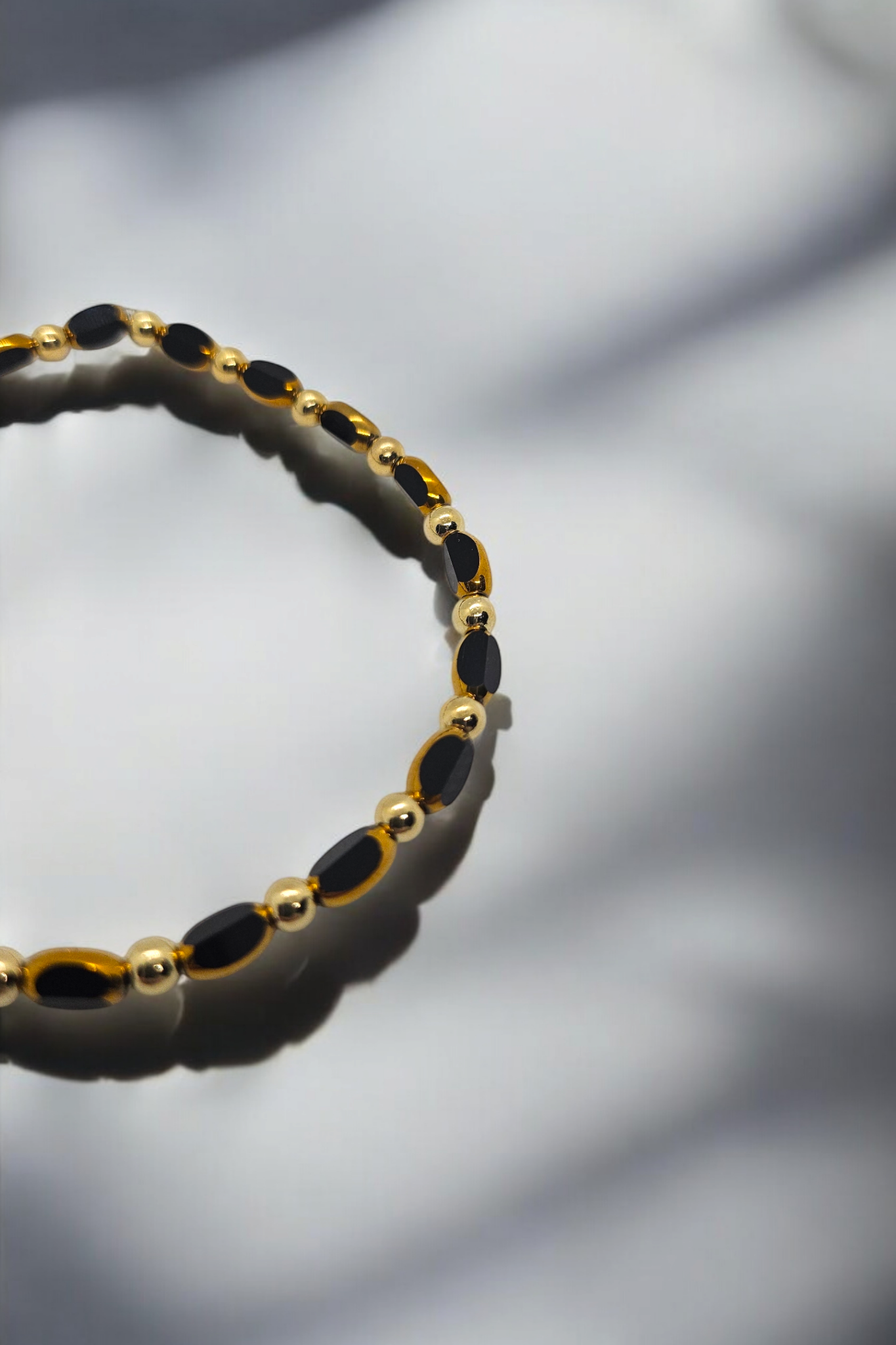 Elastieken armband met gouden en zwarte glaskralen