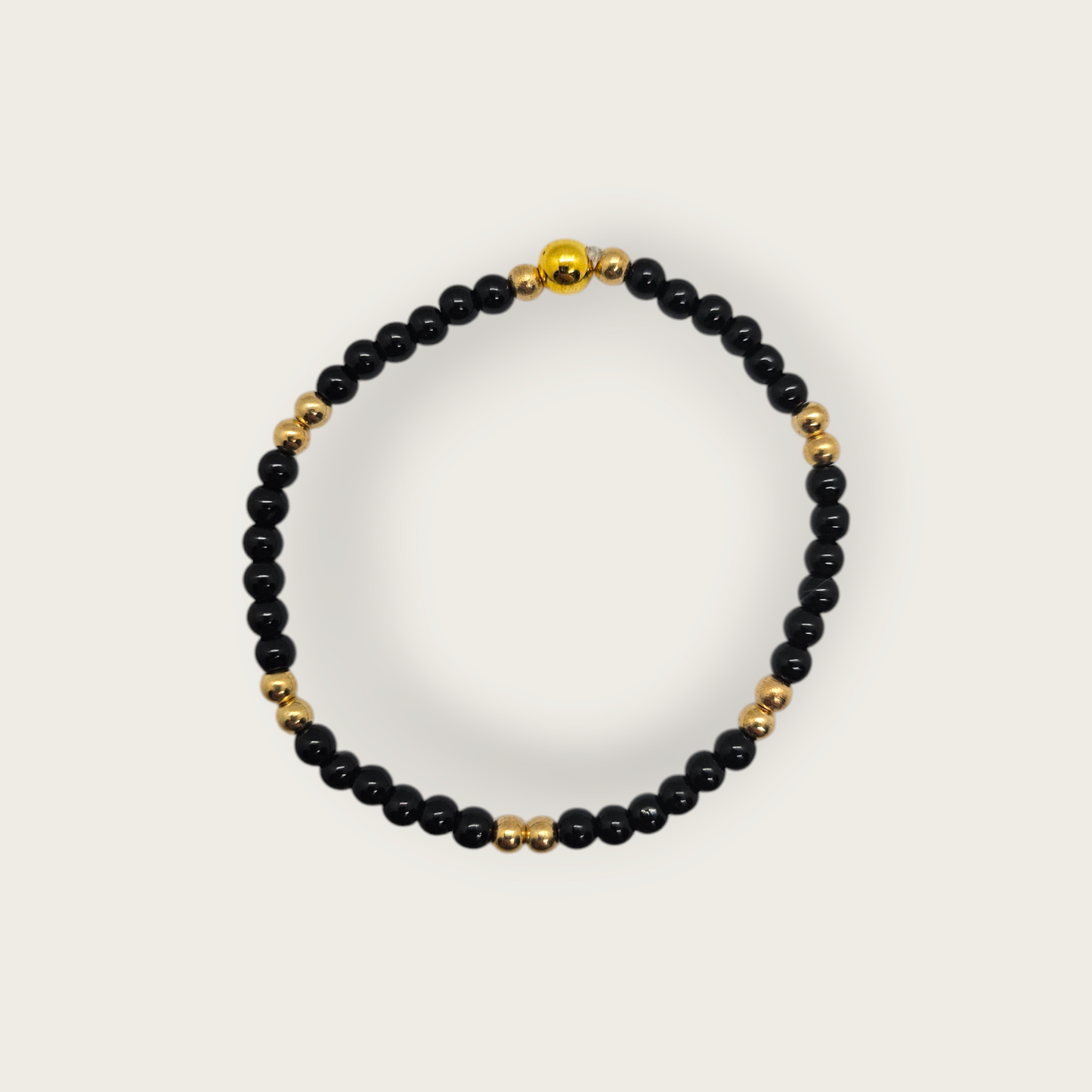 Elastieken armband met zwarte en gouden kralen