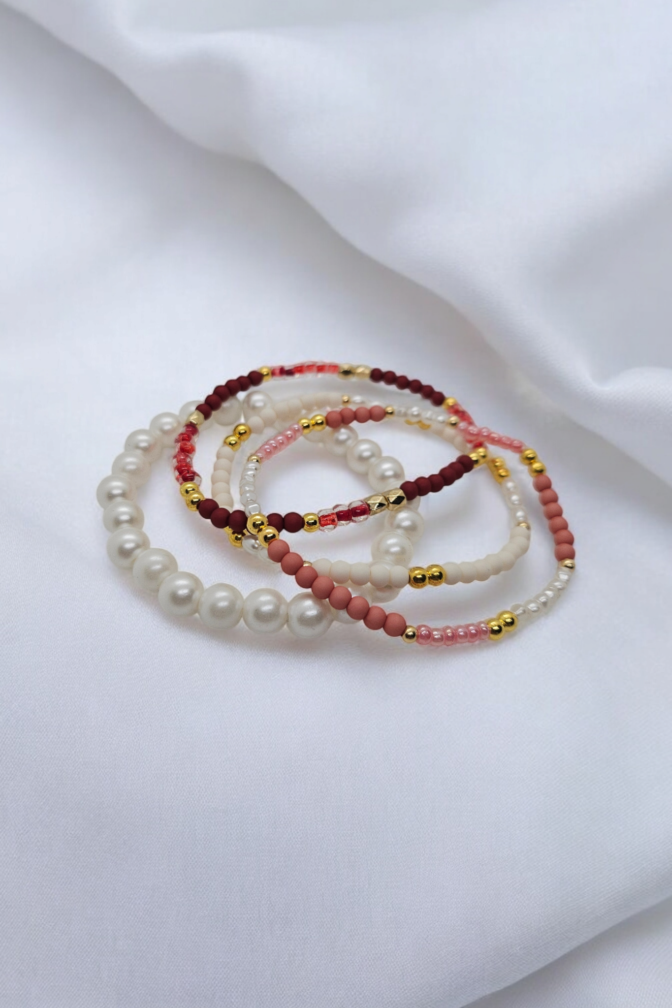 Elastieken armbanden met roze kralen, witte parels en goudkleurige details