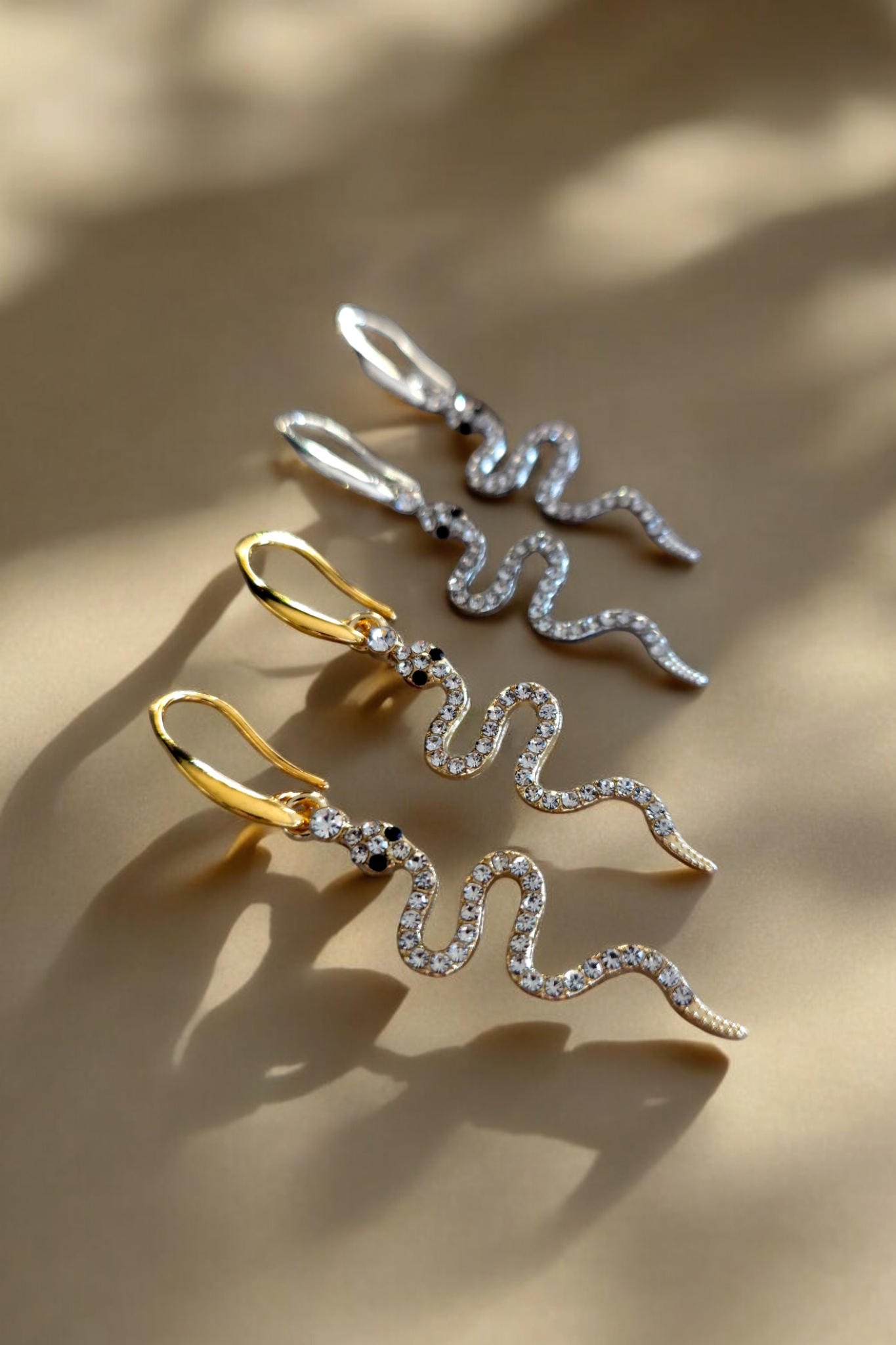 Opvallende oorhangers in het goud en zilver met een glinsterend hangertje in de vorm van een slang