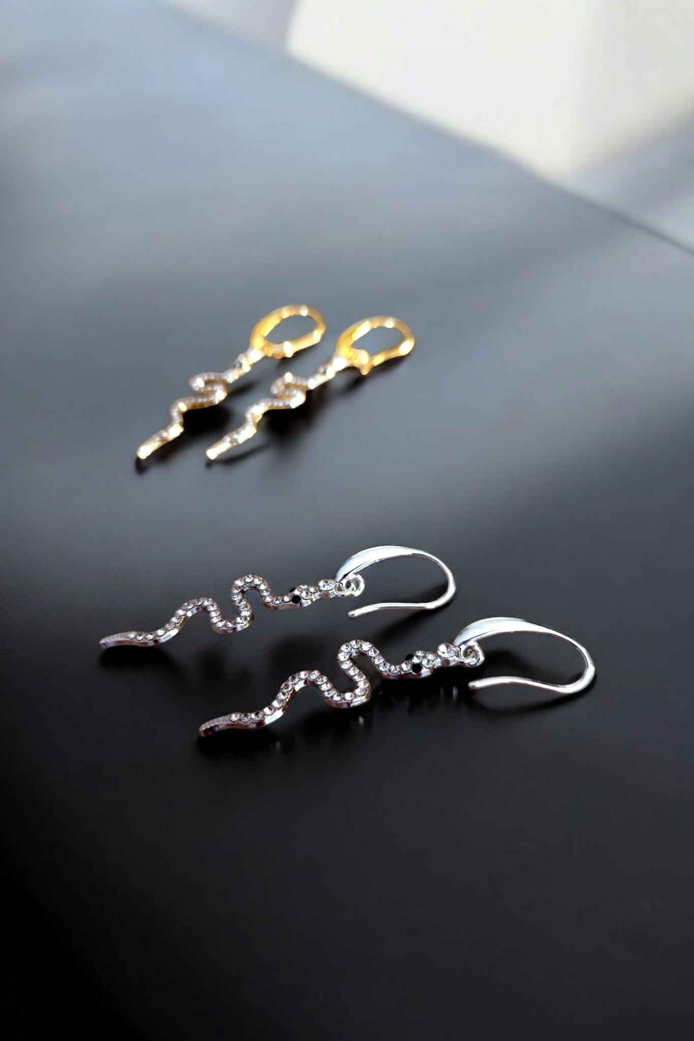 Opvallende oorbellen in zilver en goud met een glinsterende slangen hanger