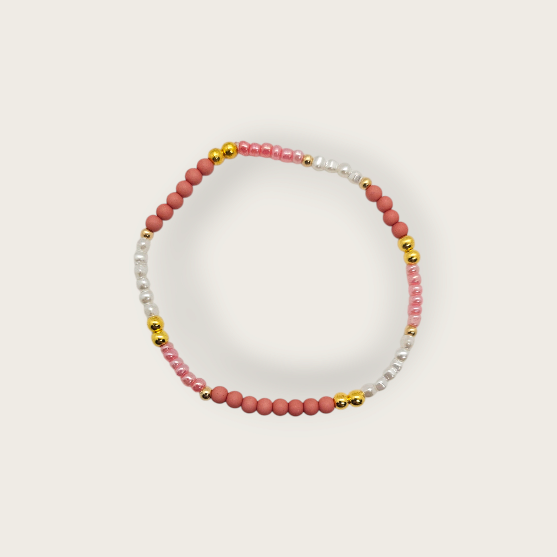 Armband van elastiek met roze kralen en goud en witte details 