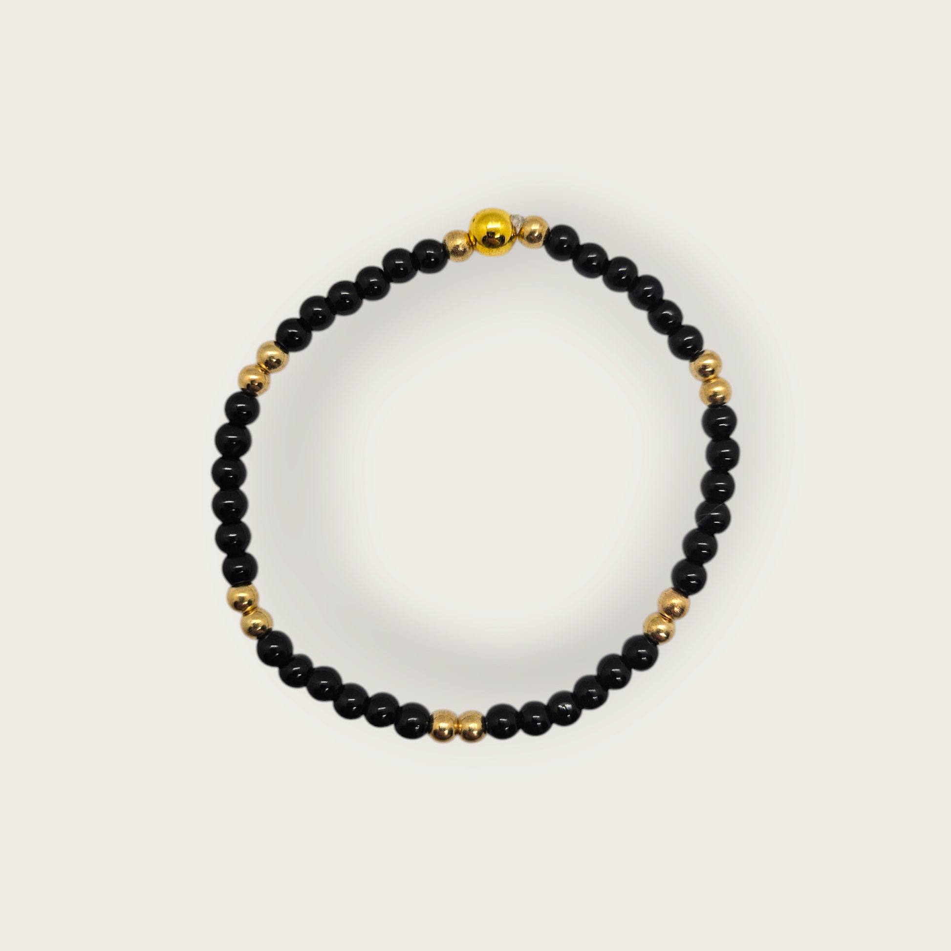Elastieken armband met zwarte en gouden kralen 