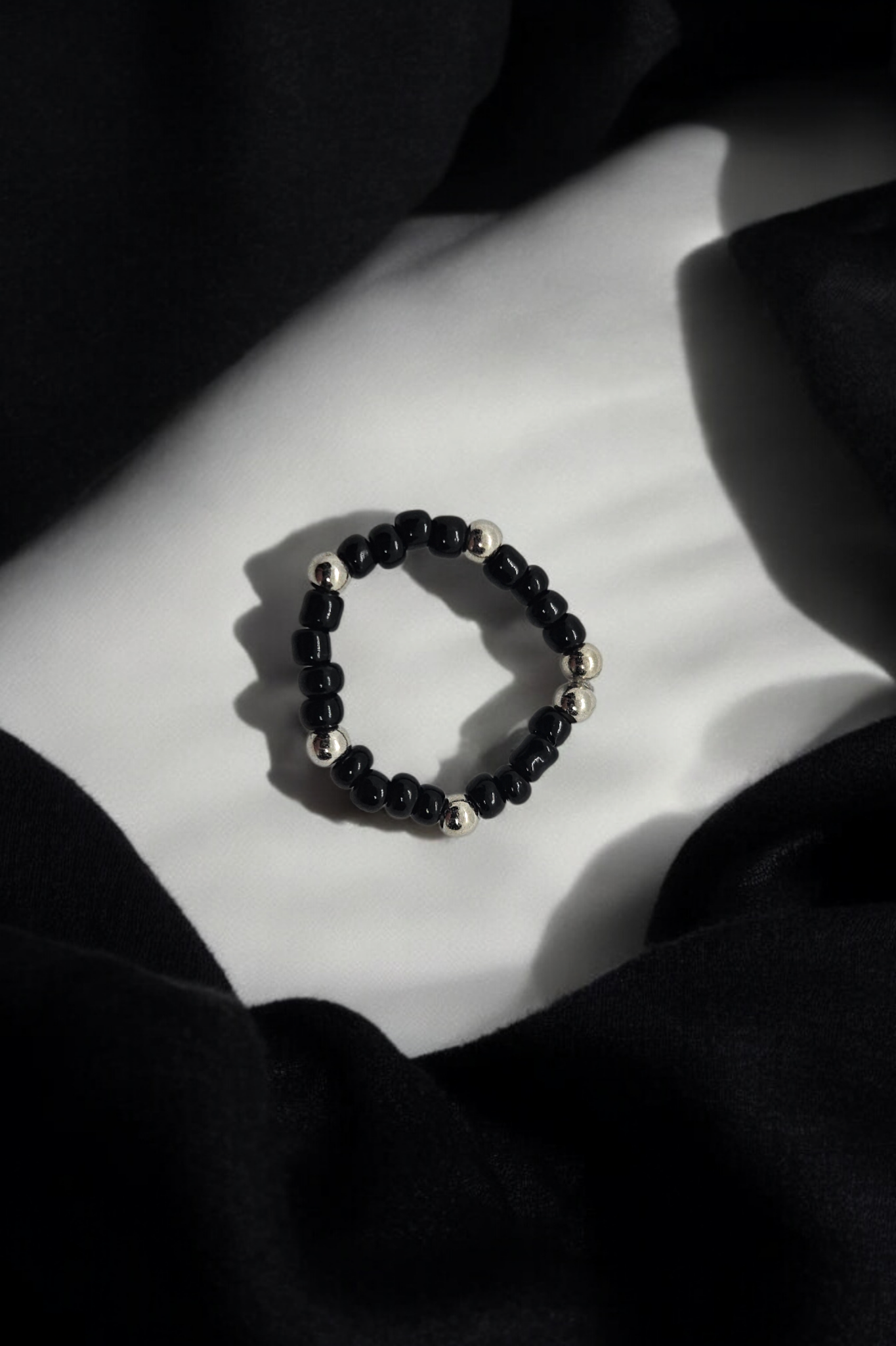 Elastieken ring met zwarte en zilveren kralen 